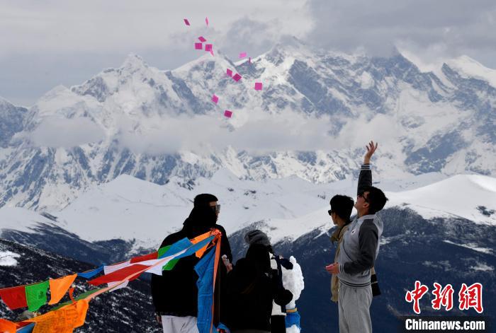 圖為5月14日，游客在西藏林芝色季拉山觀景臺(tái)拋灑“隆達(dá)”(風(fēng)馬旗，藏族民眾的一種祈福方式)。　李林 攝