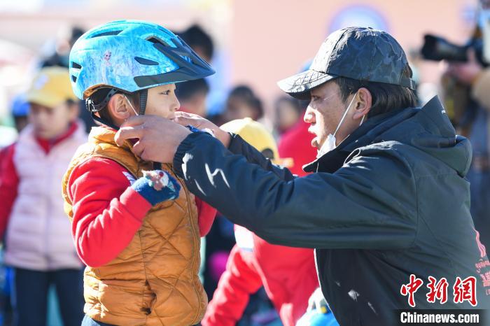 圖為拉薩市實(shí)驗(yàn)幼兒園孩子在教練的幫助下穿戴頭盔?！『闻罾?攝